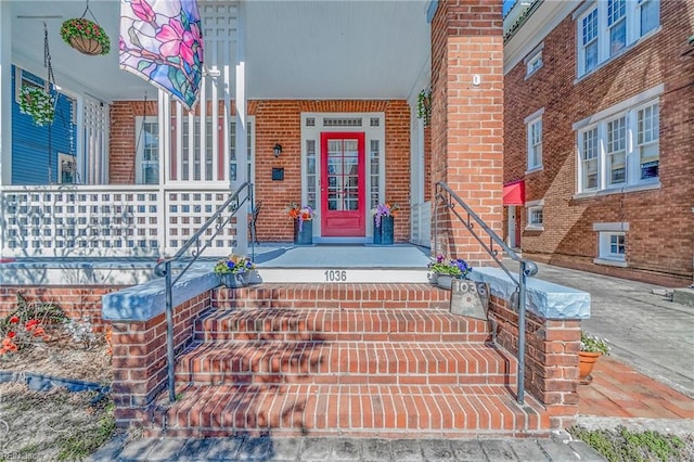 view of exterior entry with covered porch and brick siding