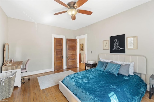 bedroom with wood-type flooring, baseboards, and a ceiling fan