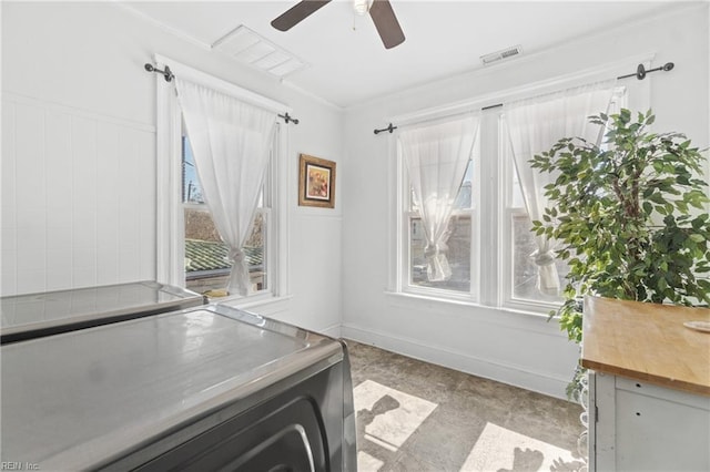 unfurnished office featuring plenty of natural light, washing machine and clothes dryer, visible vents, and a ceiling fan