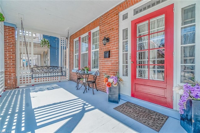 entrance to property featuring a porch and brick siding