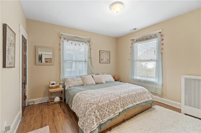 bedroom with wood finished floors, visible vents, and baseboards