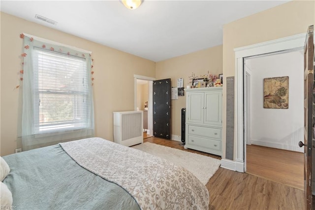 bedroom with baseboards, visible vents, and wood finished floors