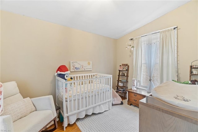 bedroom featuring a nursery area and wood finished floors