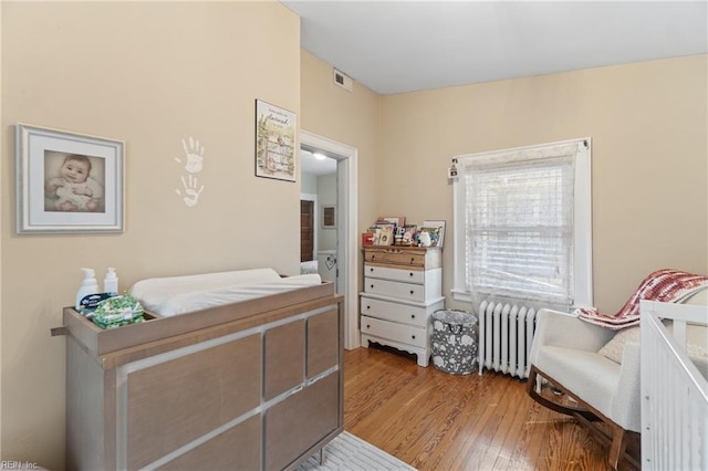 bedroom featuring hardwood / wood-style floors, radiator heating unit, and visible vents