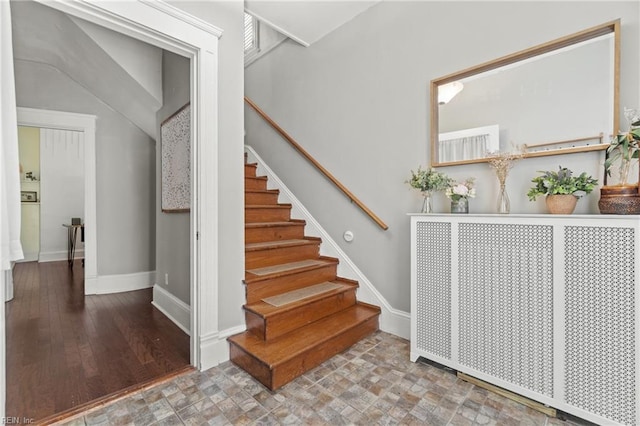 stairway with stone finish floor and baseboards