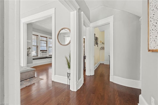 hall featuring lofted ceiling, baseboards, and wood finished floors