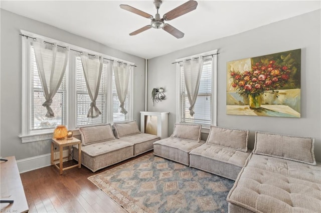 living area featuring baseboards, ceiling fan, and hardwood / wood-style floors