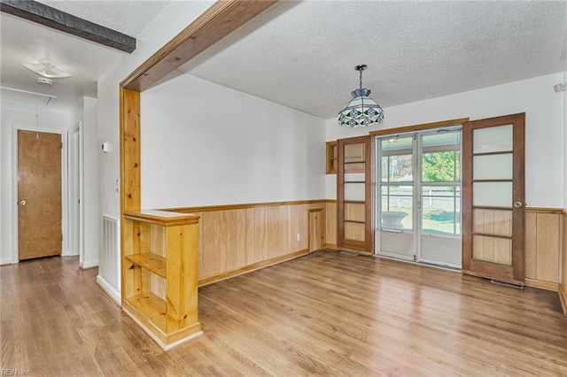 empty room featuring attic access, wainscoting, and a textured ceiling