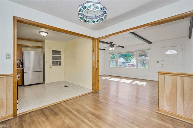 kitchen with beam ceiling, light wood finished floors, freestanding refrigerator, ceiling fan, and baseboards