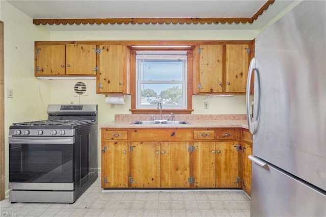 kitchen with appliances with stainless steel finishes, light countertops, brown cabinetry, and a sink