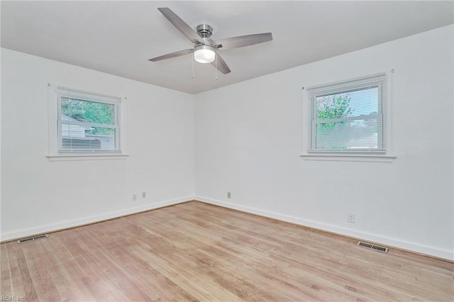 unfurnished room with a healthy amount of sunlight, visible vents, baseboards, and wood finished floors