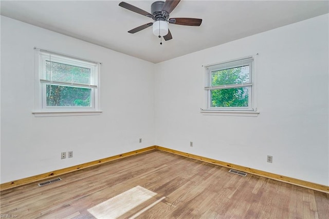 unfurnished room featuring plenty of natural light, visible vents, and wood finished floors