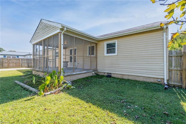 back of property with a sunroom, fence, and a lawn