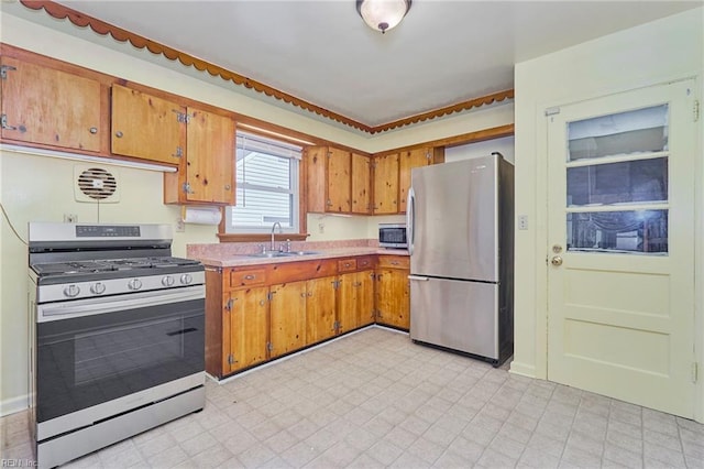 kitchen with light floors, appliances with stainless steel finishes, a sink, and light countertops