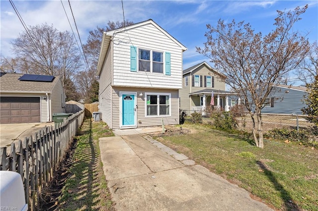 view of front of house featuring solar panels, a front lawn, concrete driveway, and fence private yard