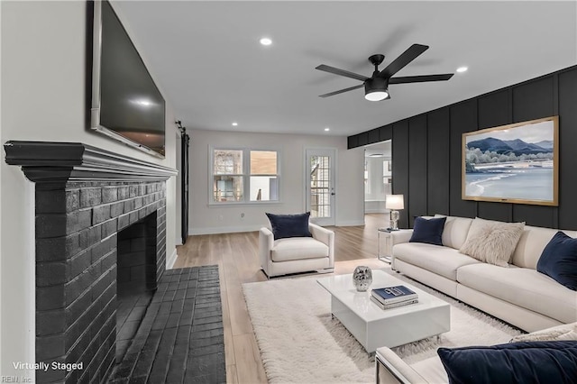 living area featuring recessed lighting, a fireplace, a ceiling fan, baseboards, and light wood-type flooring