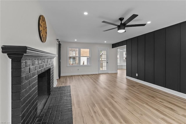 unfurnished living room with recessed lighting, light wood-style floors, a brick fireplace, ceiling fan, and baseboards