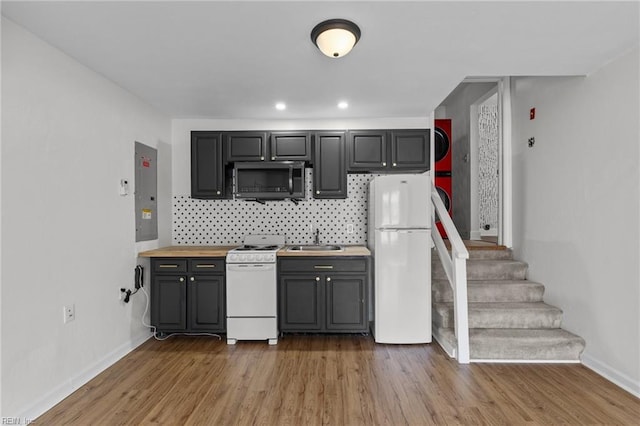 kitchen with white appliances, a sink, light wood-style flooring, and decorative backsplash