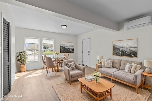 living area with an AC wall unit, light wood finished floors, and baseboards