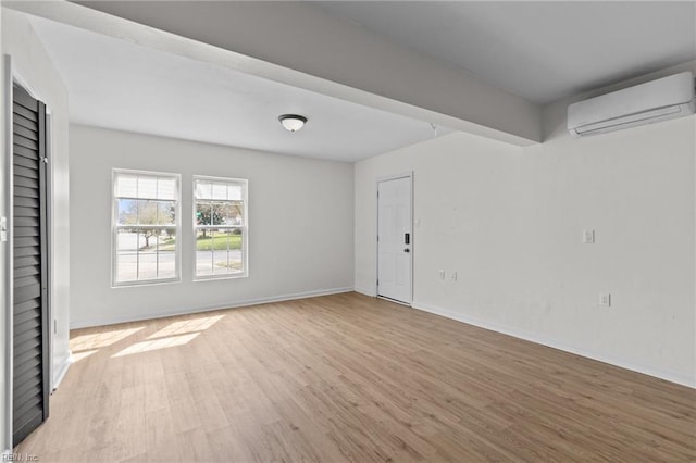 empty room with light wood-style flooring, baseboards, and an AC wall unit