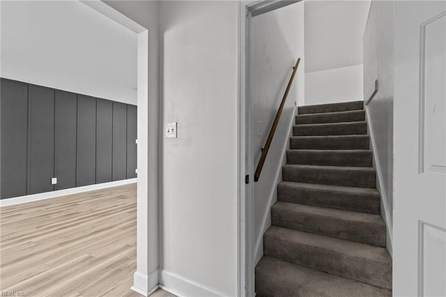 staircase featuring wood finished floors and baseboards