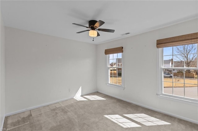 carpeted spare room featuring visible vents, ceiling fan, and baseboards