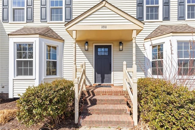 doorway to property with roof with shingles