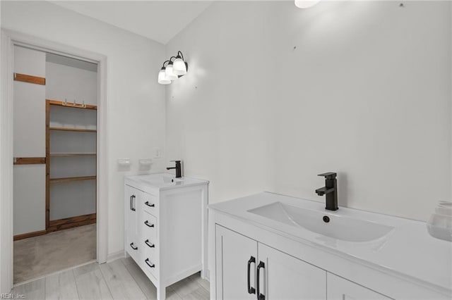 full bath featuring a walk in closet, two vanities, and a sink