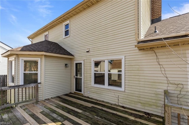 back of property featuring a deck and roof with shingles