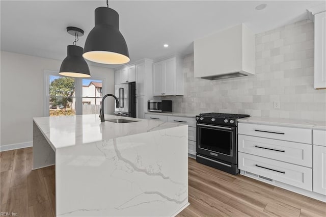 kitchen featuring appliances with stainless steel finishes, custom range hood, light wood-style floors, and decorative backsplash