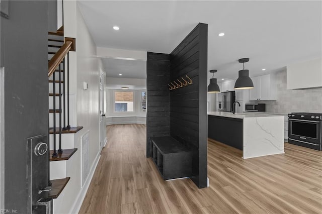 interior space featuring recessed lighting, light wood-style floors, a sink, baseboards, and stairs