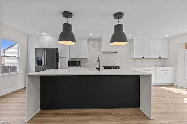 kitchen with white cabinetry, high end fridge, light wood-type flooring, decorative backsplash, and stainless steel microwave