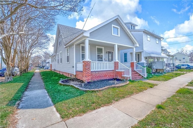 bungalow-style house featuring a shingled roof, a porch, and a front yard