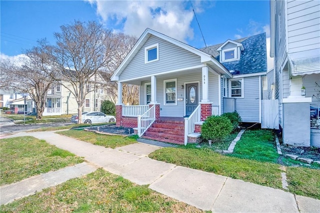 bungalow-style house with a porch, a front lawn, and a shingled roof