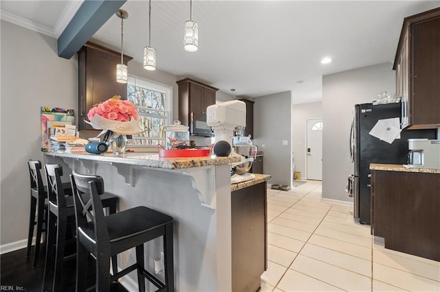 kitchen featuring black microwave, light tile patterned floors, a peninsula, a kitchen breakfast bar, and dark brown cabinets