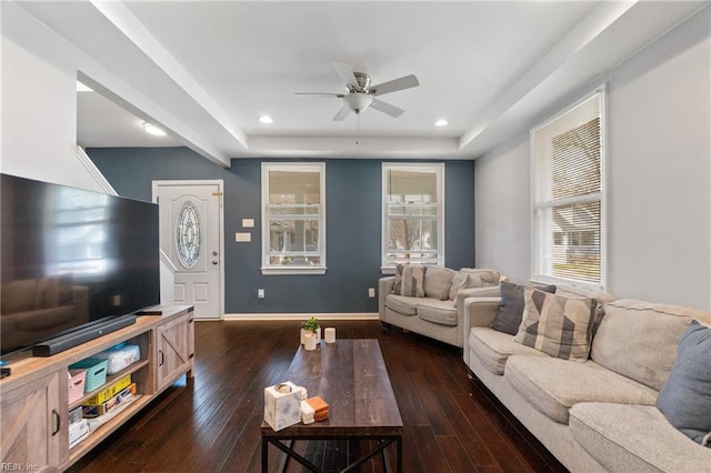 living room featuring wood-type flooring, baseboards, a raised ceiling, and recessed lighting