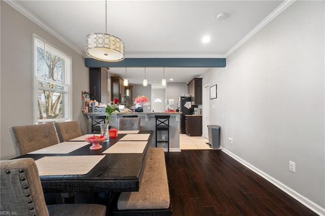 dining space with crown molding, baseboards, and wood finished floors