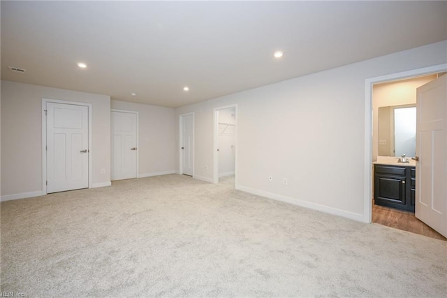 unfurnished bedroom featuring baseboards, recessed lighting, connected bathroom, and light colored carpet