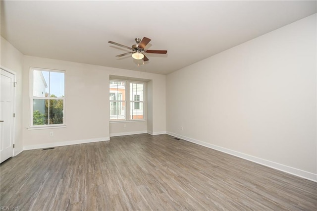 empty room featuring visible vents, baseboards, ceiling fan, and wood finished floors