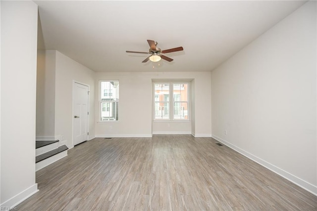 unfurnished living room featuring wood finished floors, a ceiling fan, and baseboards