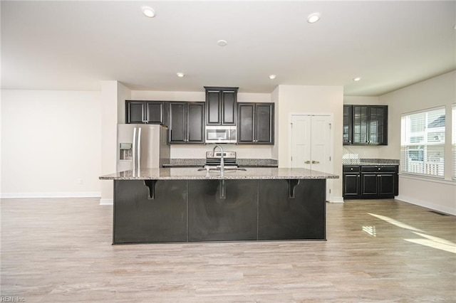 kitchen with appliances with stainless steel finishes, a spacious island, a sink, and a breakfast bar