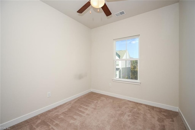 spare room featuring light carpet, ceiling fan, visible vents, and baseboards