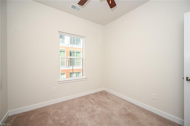 carpeted spare room with a ceiling fan, visible vents, and baseboards