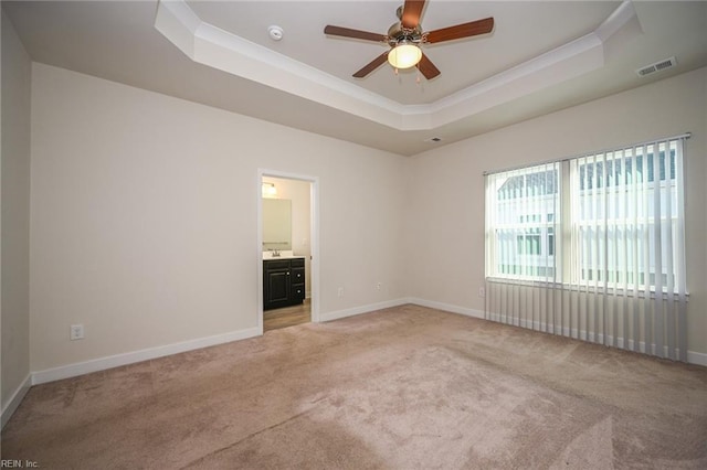 spare room with baseboards, a raised ceiling, visible vents, and light colored carpet