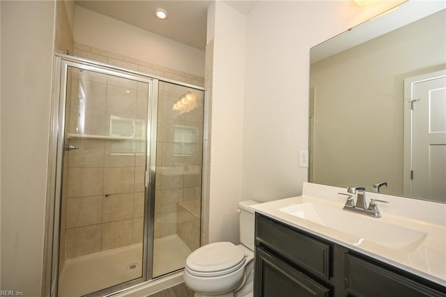 bathroom featuring toilet, a stall shower, and vanity