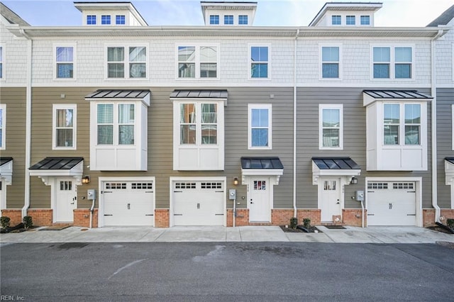 townhome / multi-family property with a garage, a standing seam roof, and brick siding