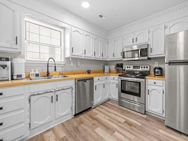 kitchen with appliances with stainless steel finishes, a sink, visible vents, and white cabinetry