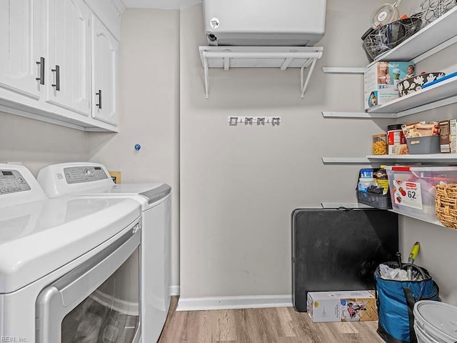 laundry room with light wood-type flooring, washing machine and dryer, cabinet space, and baseboards