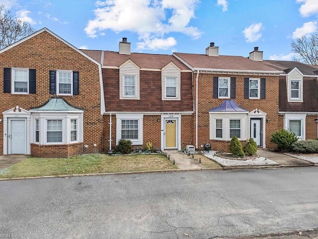 multi unit property featuring brick siding, a chimney, a gambrel roof, and roof with shingles