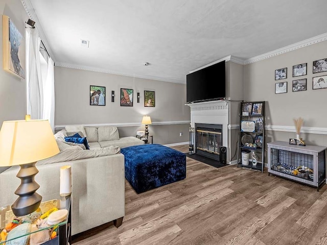 living room with a fireplace with flush hearth, visible vents, ornamental molding, and wood finished floors